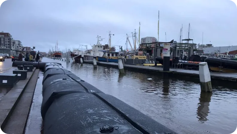 SLAMDAM flood barrier installed along a harbour quay with fishing boats