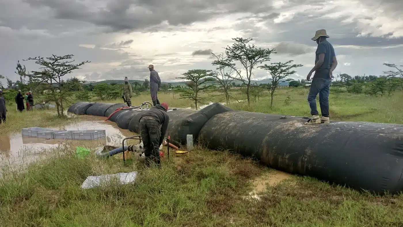 Workers preparing SLAMDAM mobile flood barriers on grassland in Laikipia, Kenya