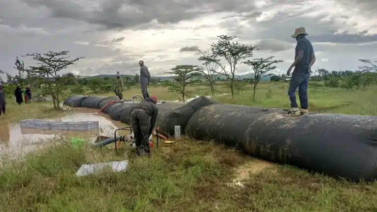 Workers preparing SLAMDAM mobile flood barriers on grassland in Laikipia, Kenya